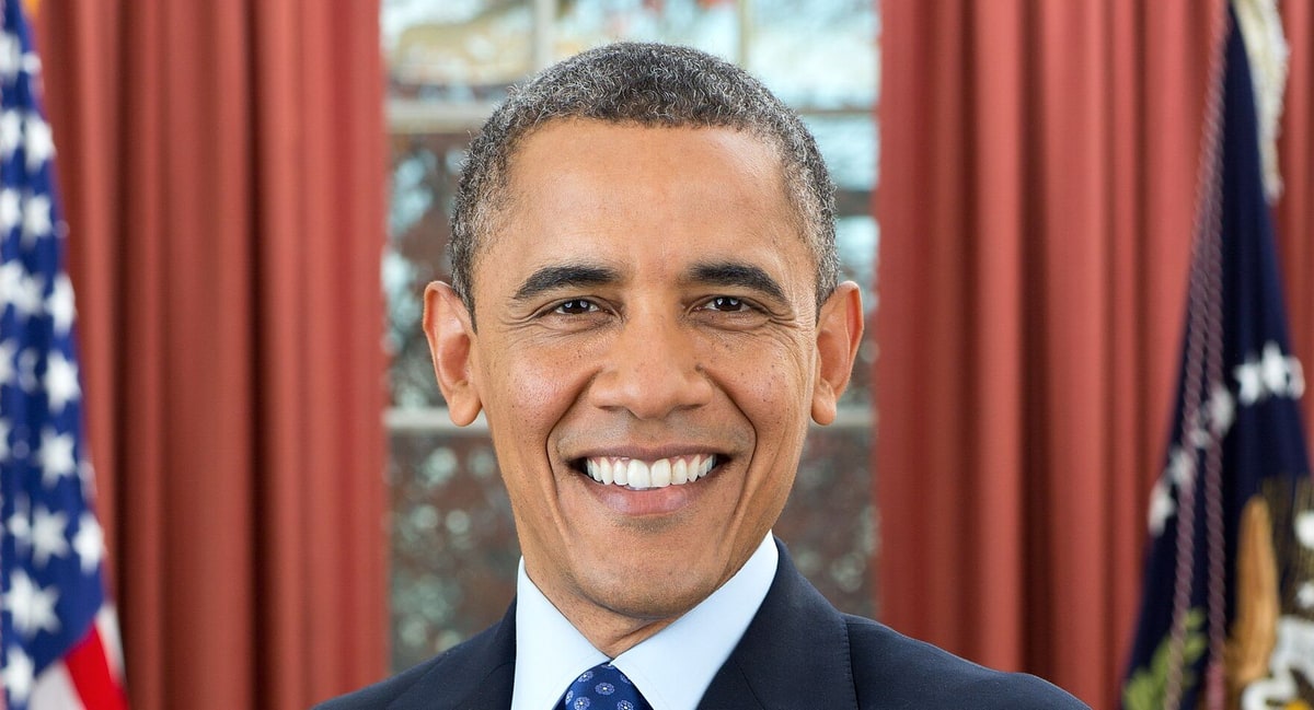 Official White House portrait of President Barack Obama smiling with arms crossed in the Oval Office, December 2012.