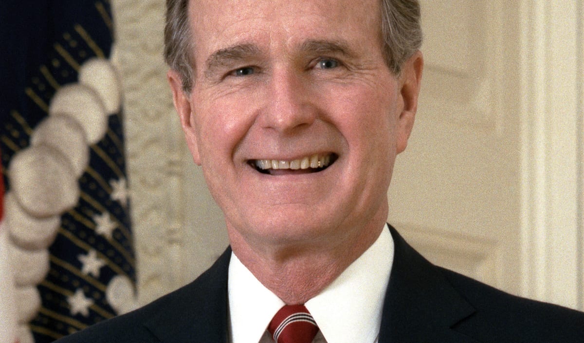 Official presidential portrait of George H. W. Bush, smiling in a dark suit and red striped tie.