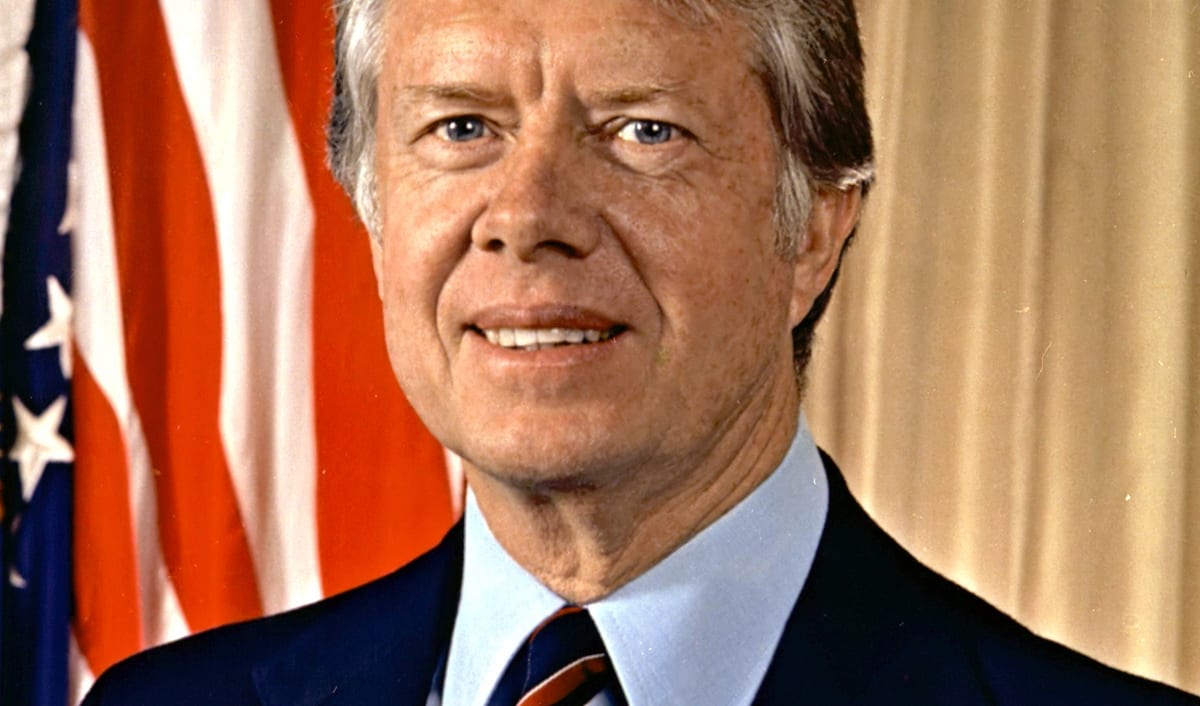 Official presidential portrait of Jimmy Carter, smiling in a dark suit with the American flag behind him.
