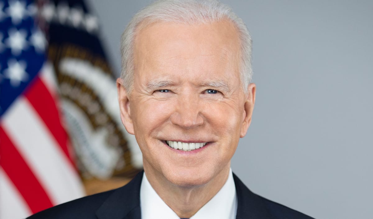 Official 2021 White House portrait of Joe Biden, smiling in a navy suit and blue tie, with the American flag and the presidential seal behind him.