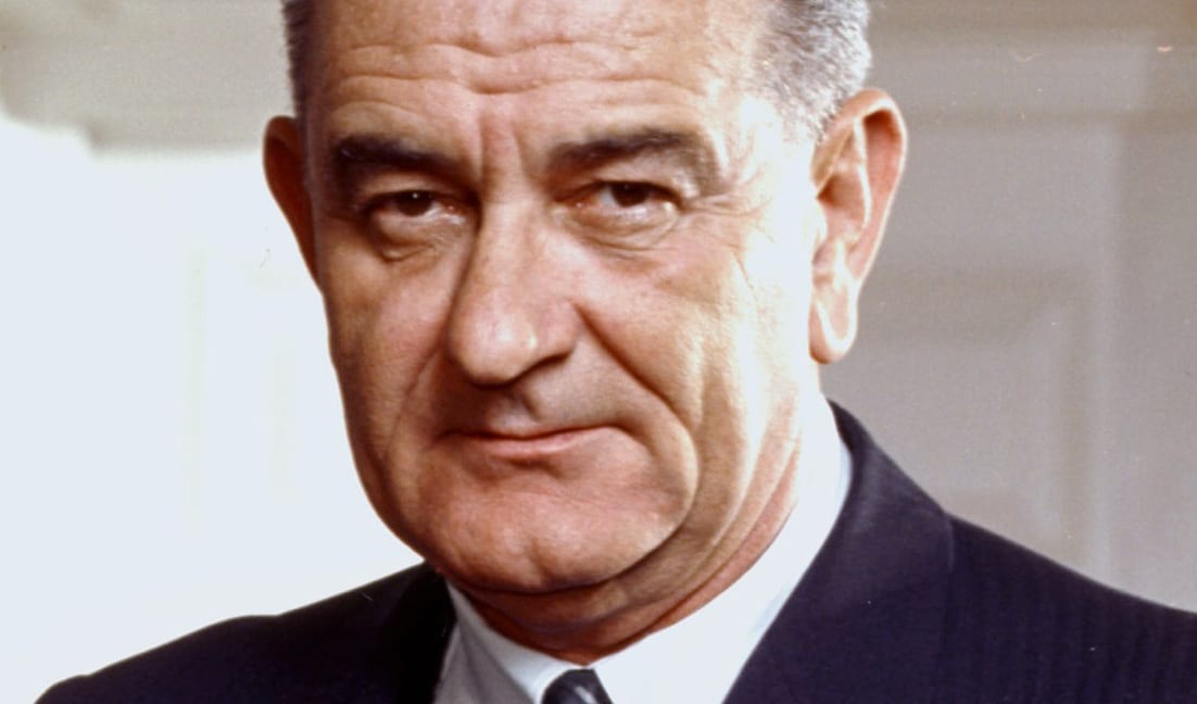 Lyndon B. Johnson in a color portrait photograph, in a dark suit and tie.
