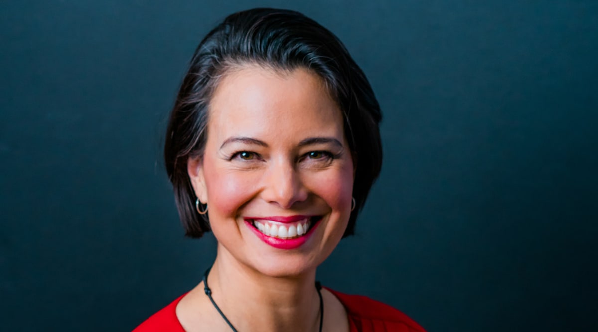 LaVeena B. Archers, PhD, smiling in a red dress against a dark teal backdrop