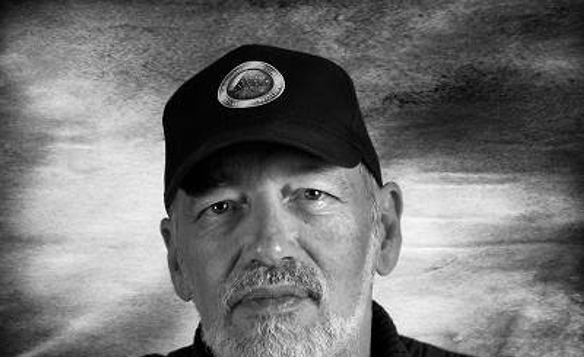 Ra Uru Hu, founder of the Human Design System, in a black cap and sweater, photographed in black and white against a textured backdrop.
